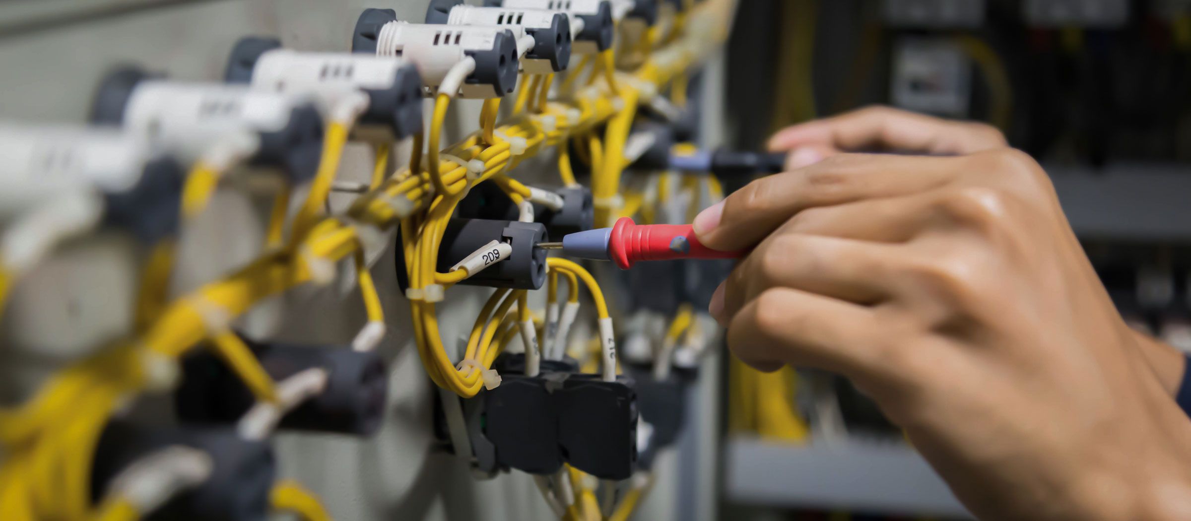 Electrician testing the current in an electrical control cabinet